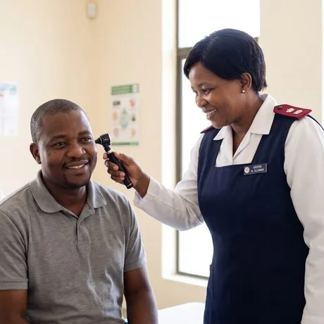 A nurse examining a worker’s ear with an otoscope